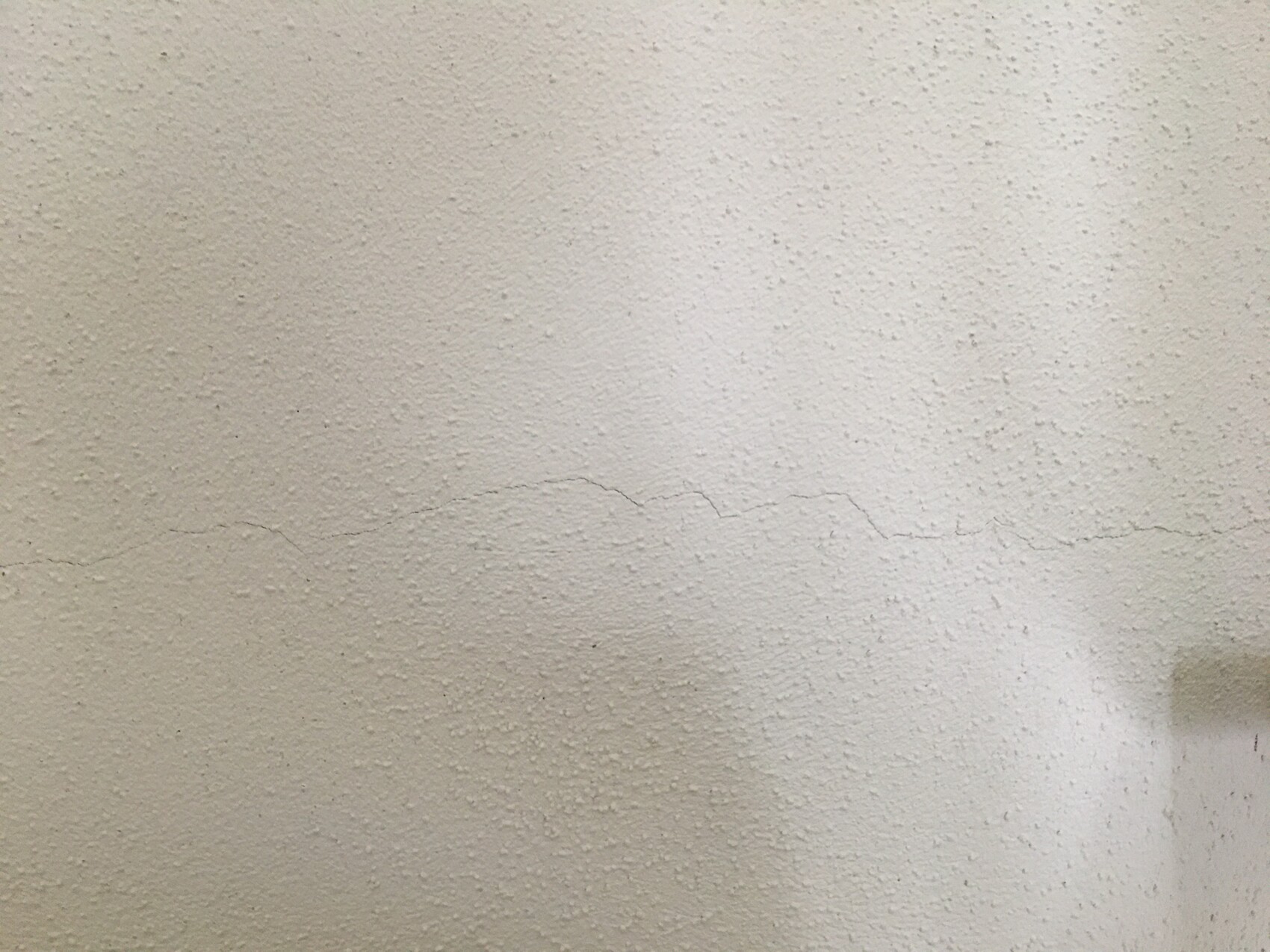 White textured wall with a fine horizontal crack line.