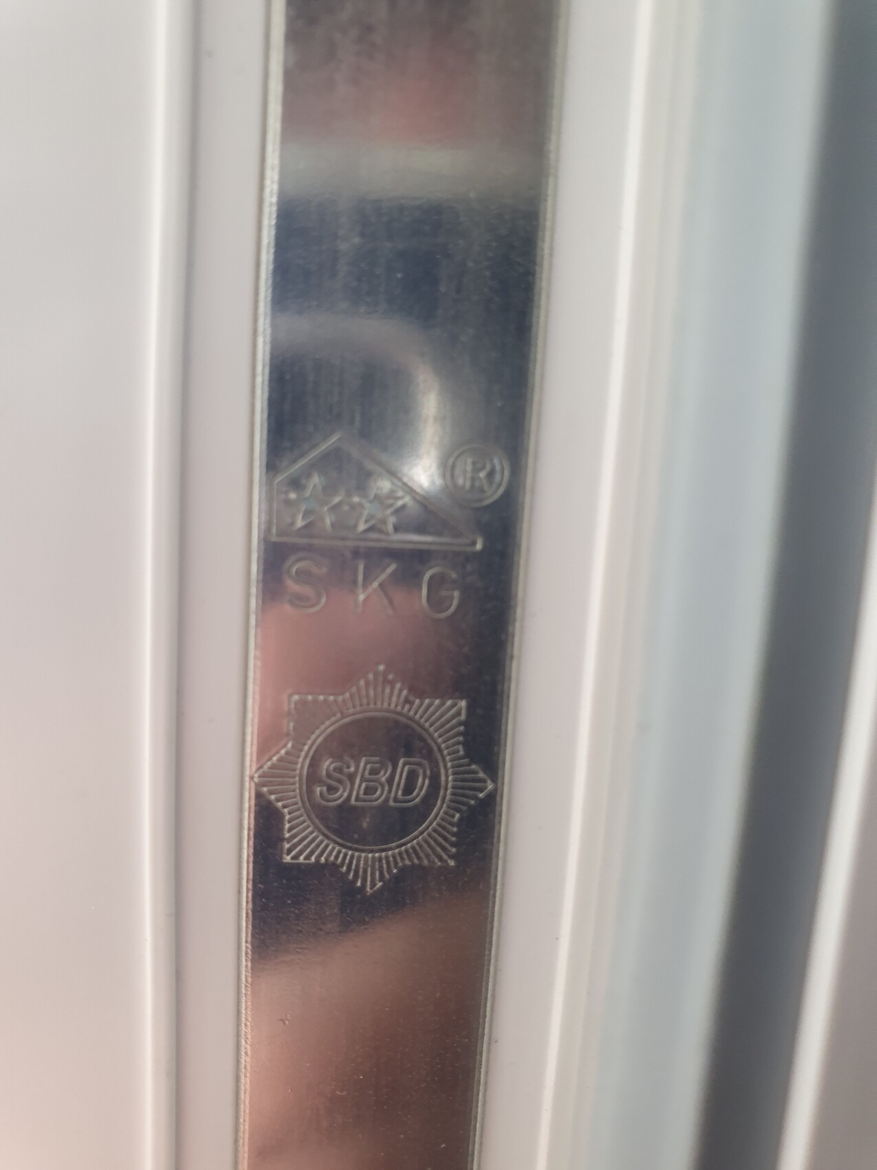 Close-up of a metal door fitting with SKG, SBD, and R seals.