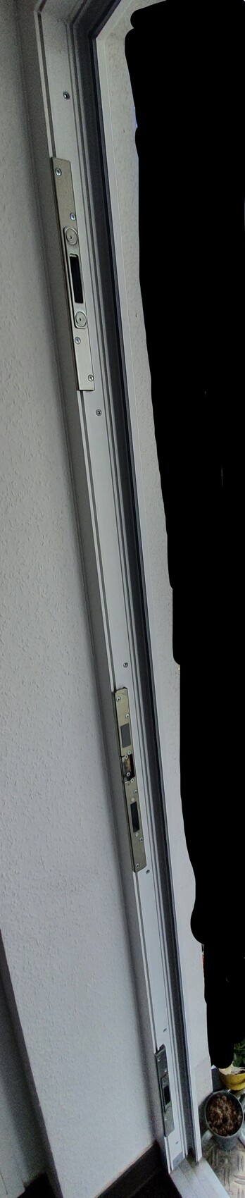 Door frame side with metal lock fitting, screws, and door edge.