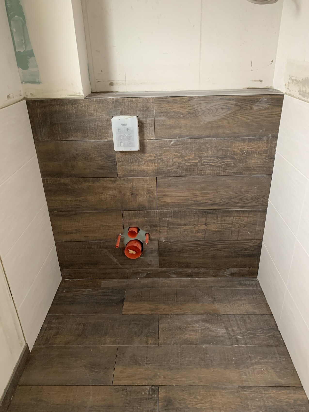 Wall with brown wood-look tiles; red installation stub at the bottom.
