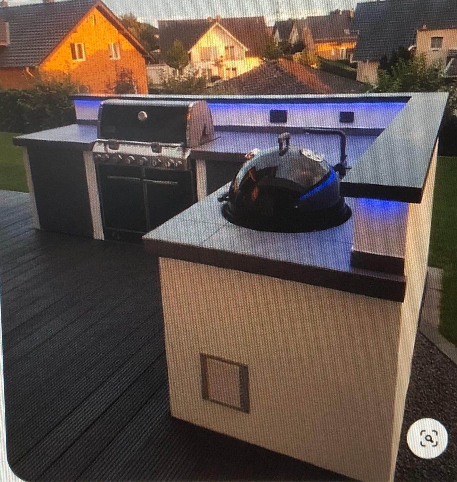 Außenküche mit Edelstahl-Grill und Kamado-Kugelgrill auf Theke, blaue LED-Beleuchtung.