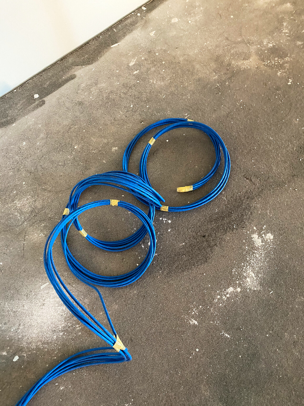 Several blue cable loops on a dark floor, some secured with yellow tape.