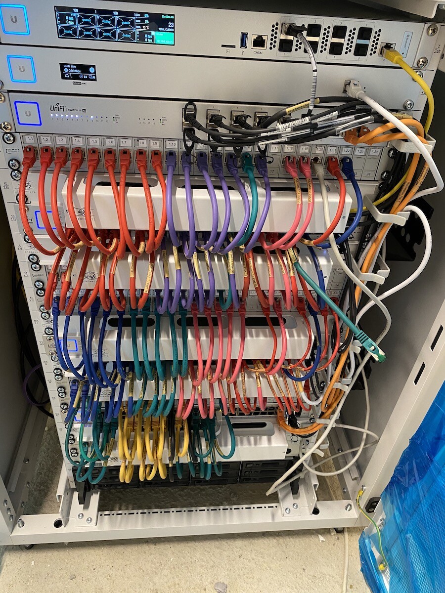 Network cabinet with many colorful Ethernet cables and server modules in the rack.