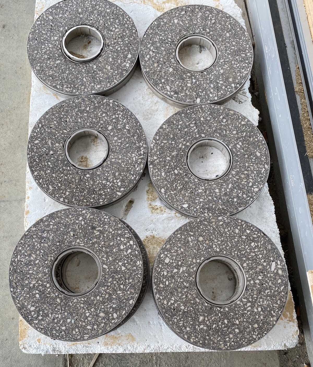 Six round granite grinding discs with holes in the middle on a light surface.