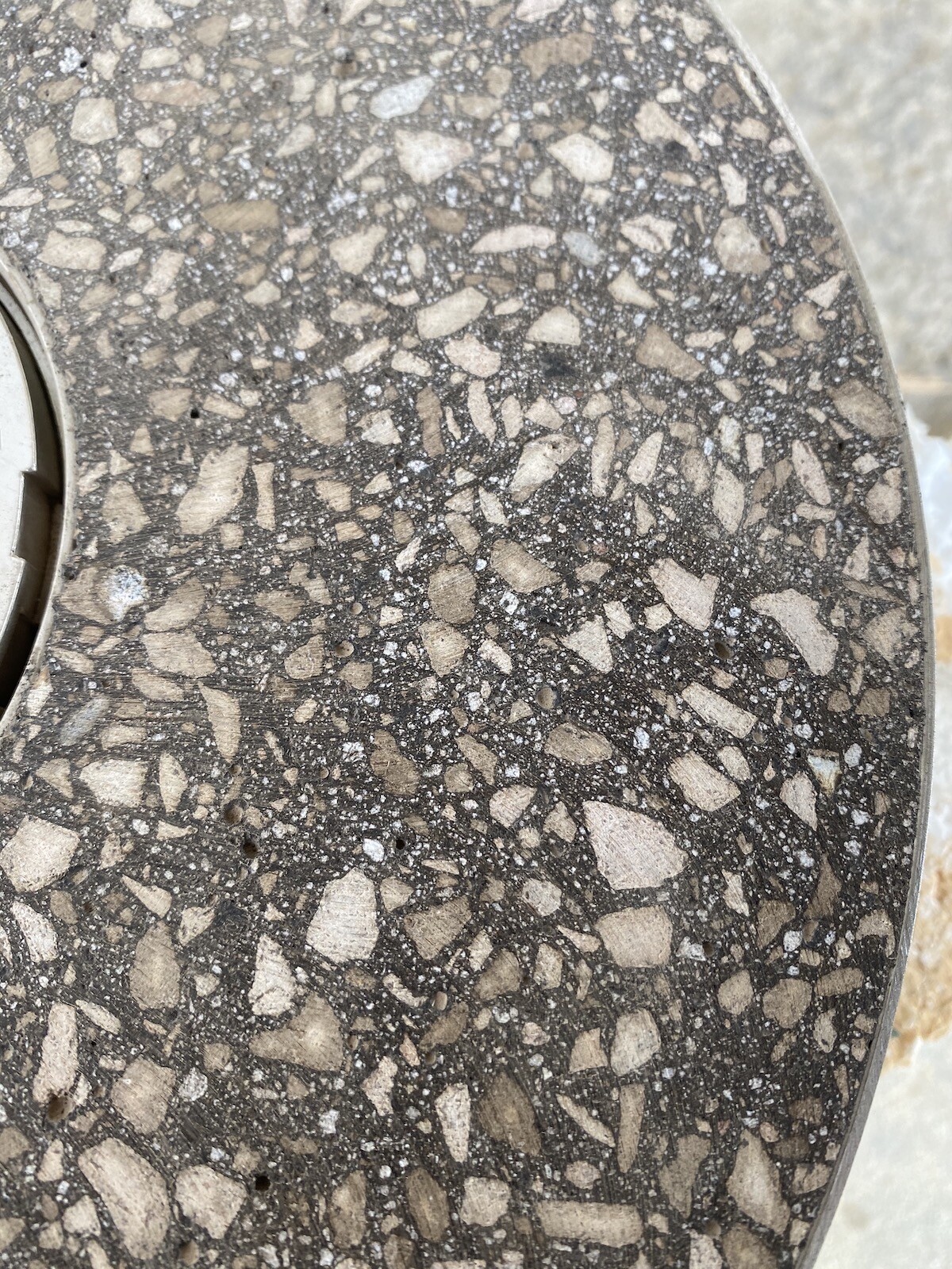 Close-up of a round concrete surface with pebbles in terrazzo style.