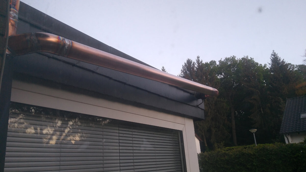 Exterior view: copper gutter above window front, blinds, garden and hedge.