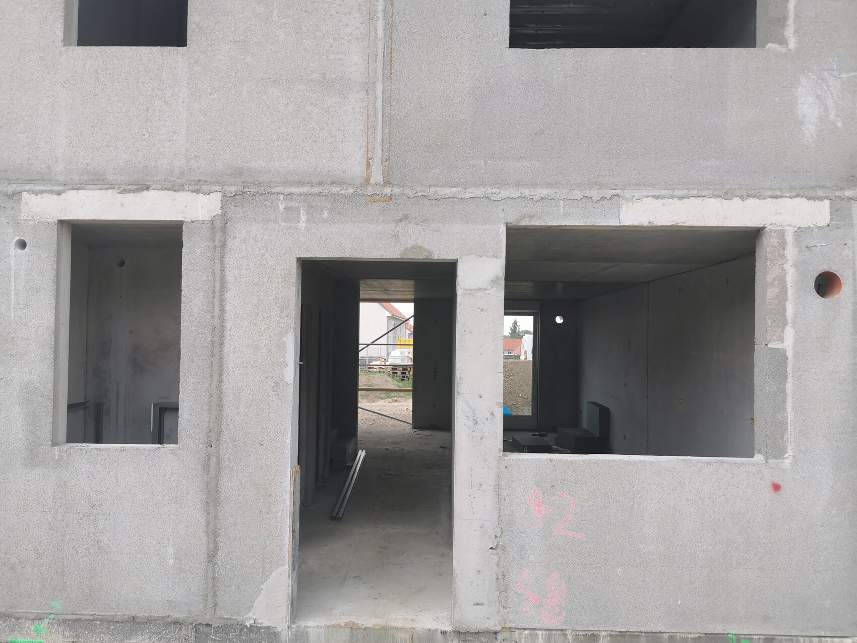 Concrete shell with open doors and window openings, interior visible through door opening.