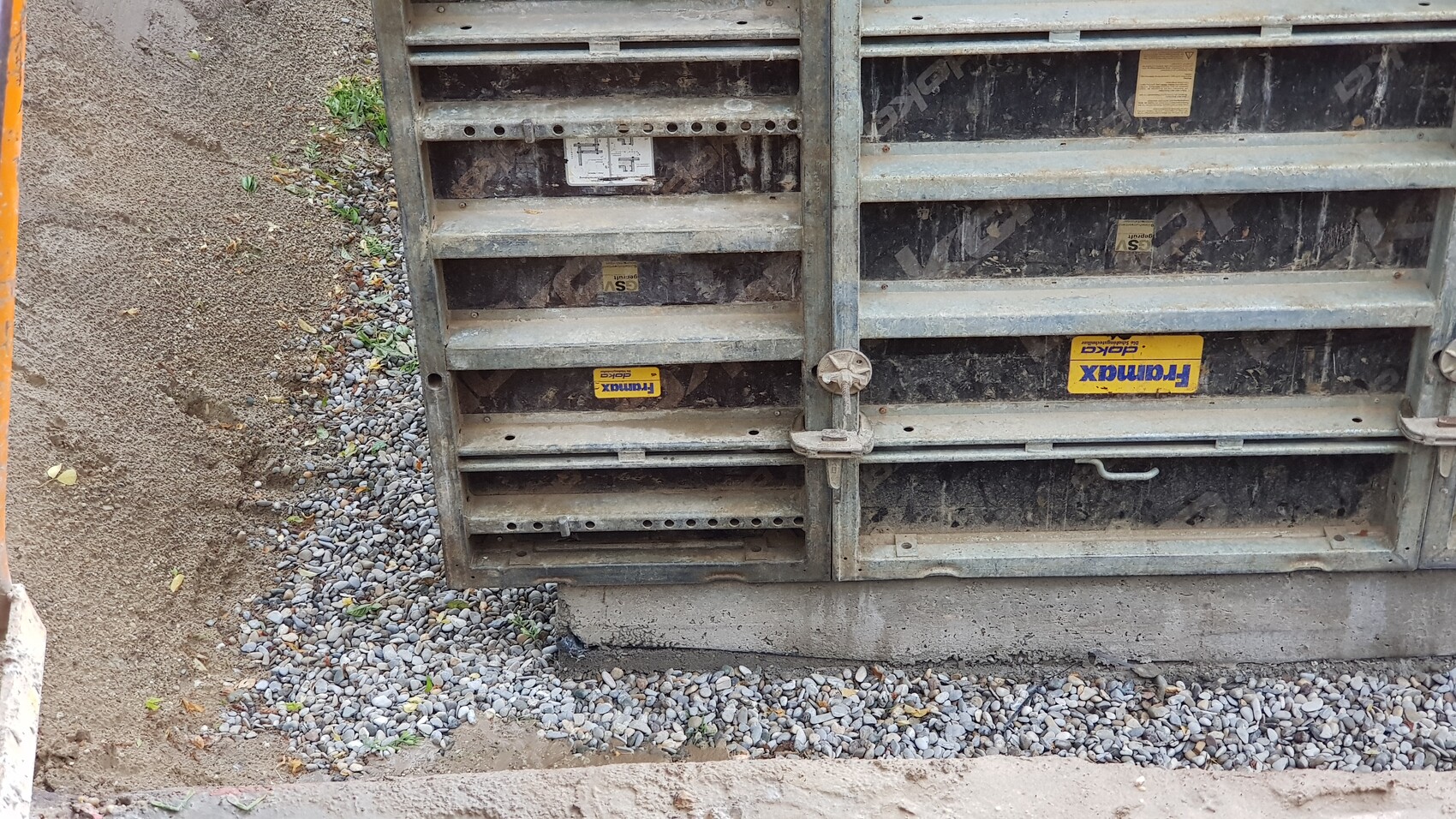 Large, dusty metal container with multiple compartments, lock in the middle, on gravel ground.