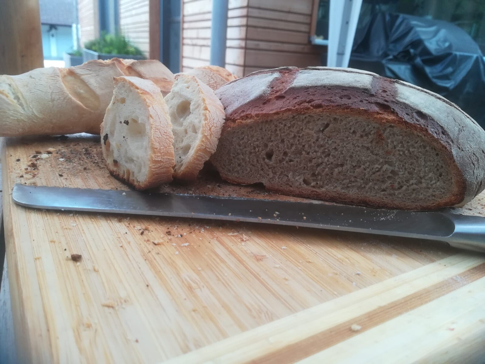 Fresh loaf of bread with slices on a cutting board, knife beside it, outside
