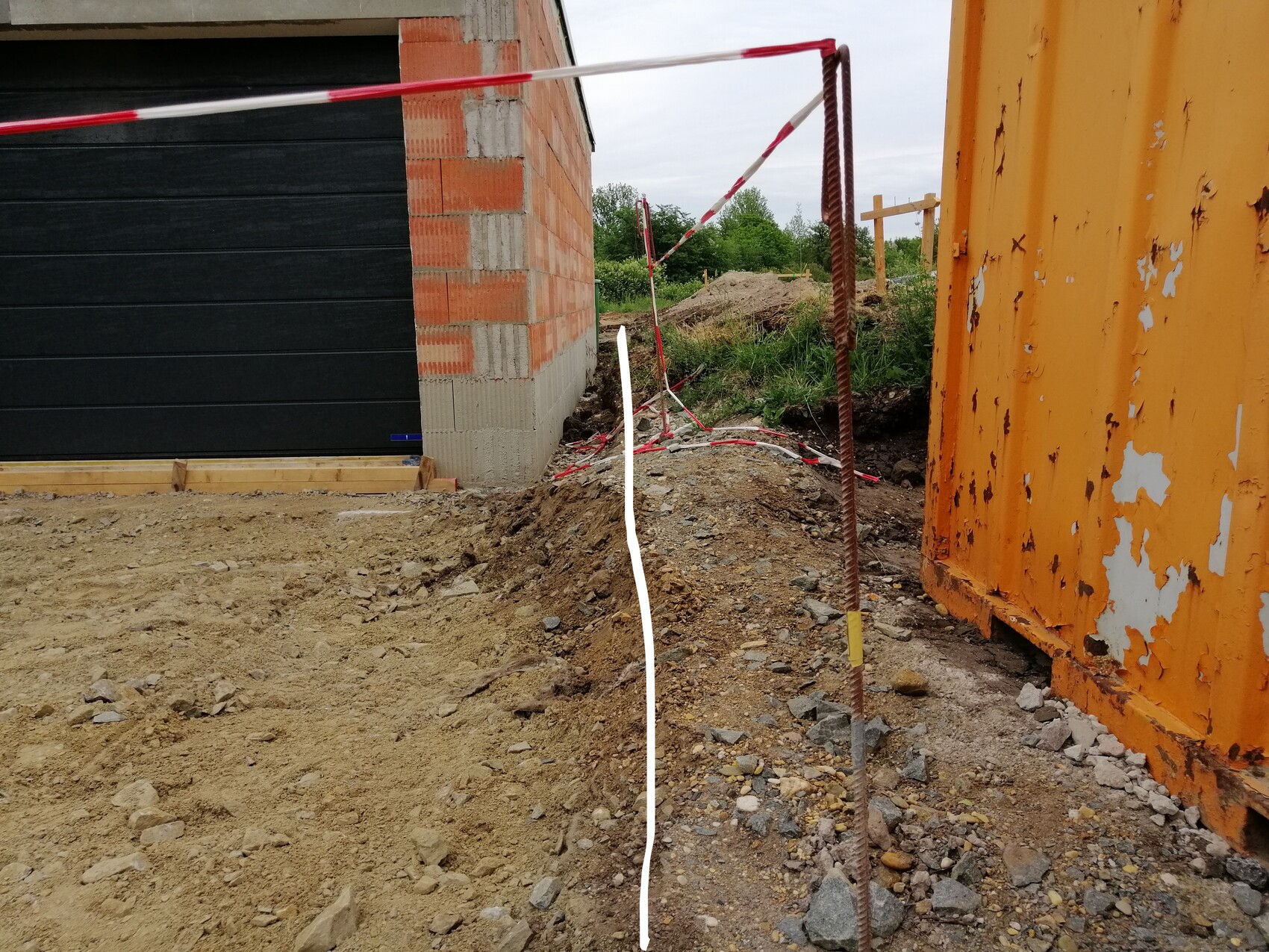 Baustelle mit Rohbaufundament, Ziegelwand, Stahlbewehrung und Absperrband