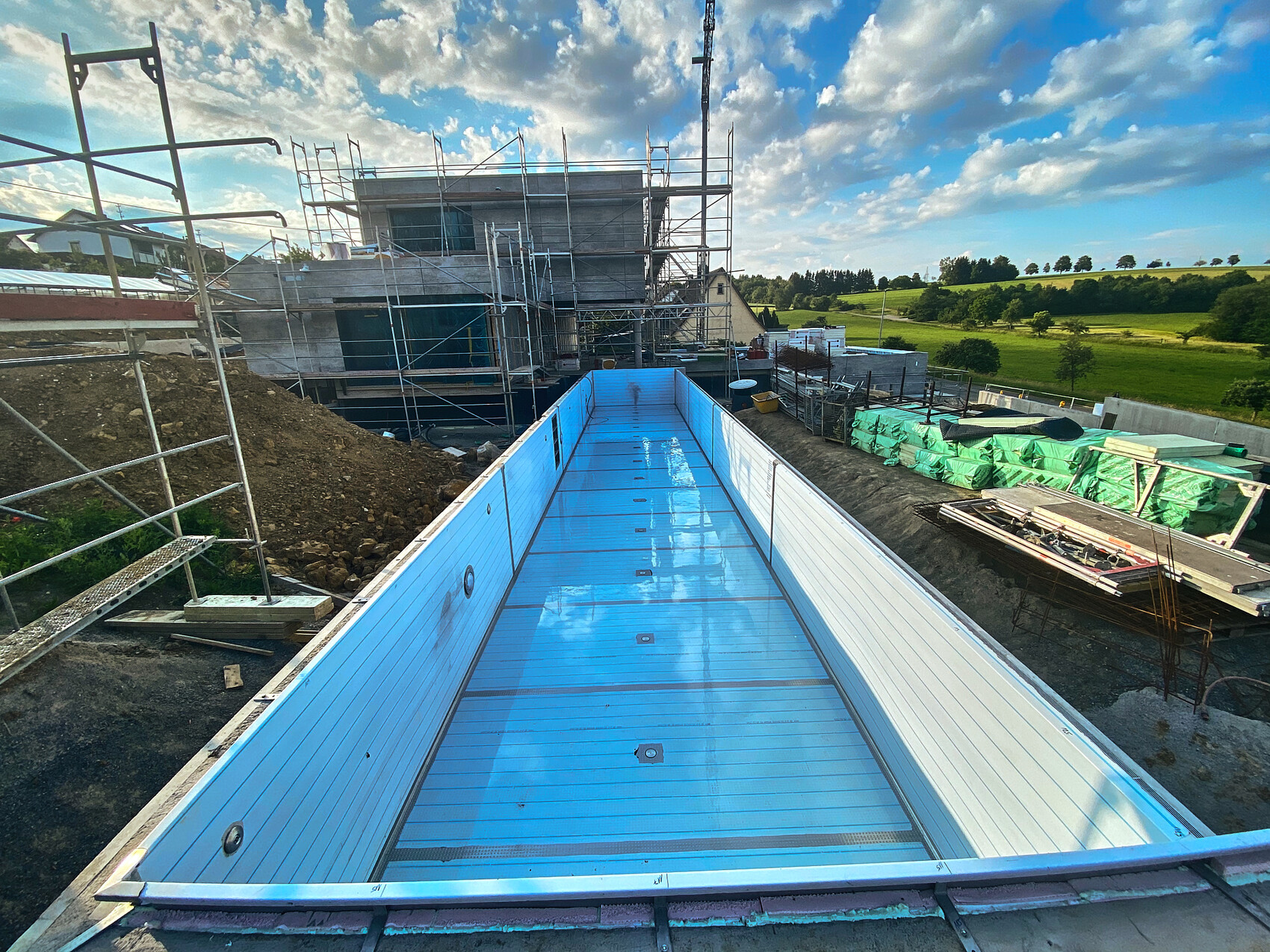 Shell construction site with scaffolding, blue basin, and green landscape in the background