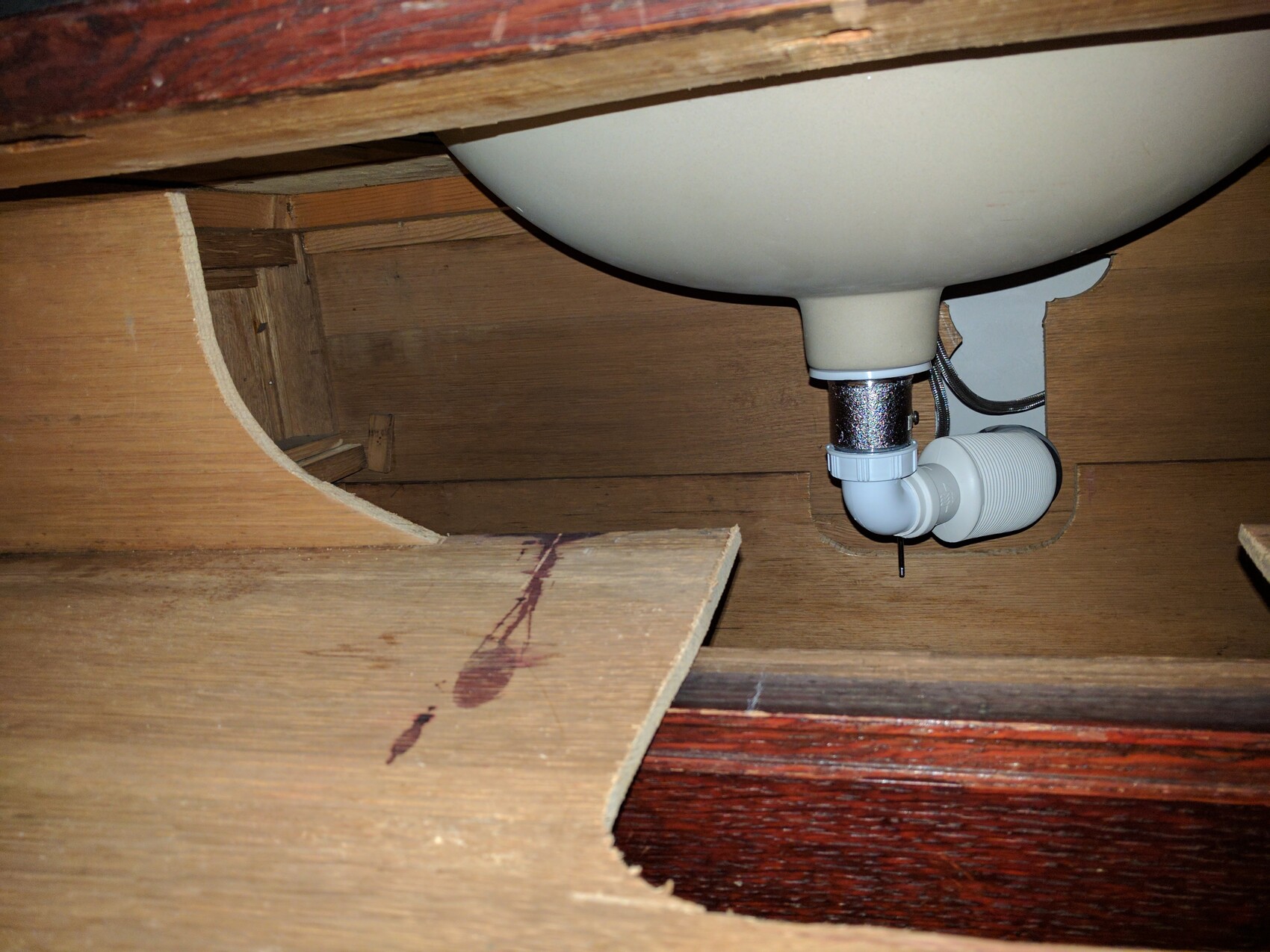 PVC trap and drain pipe visible under the sink inside the wooden cabinet.