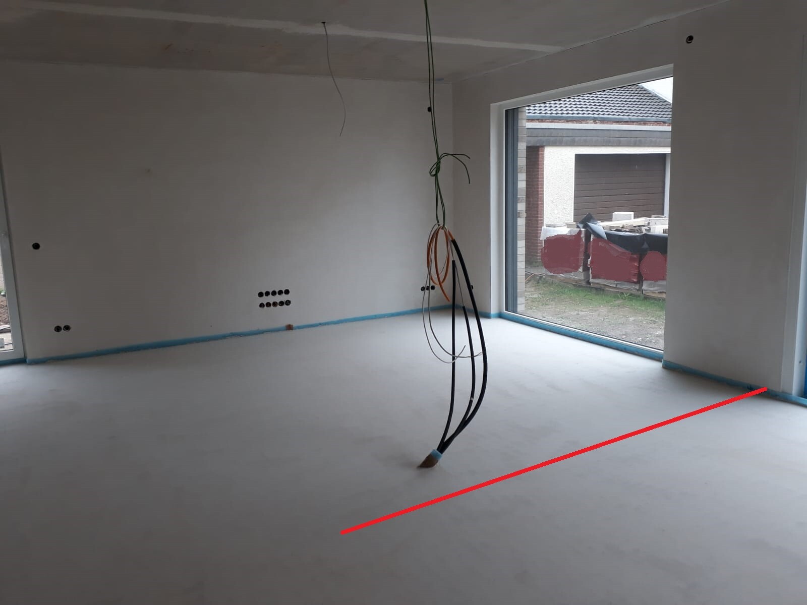 Unfinished interior with hanging cables from the ceiling, white walls, and large window front.
