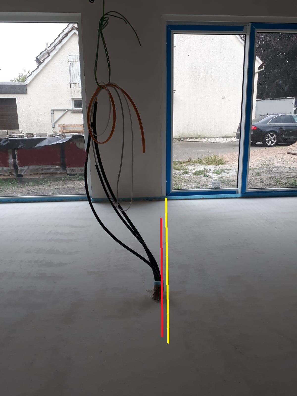Construction interior with hanging cables; red and yellow marking lines on the floor.