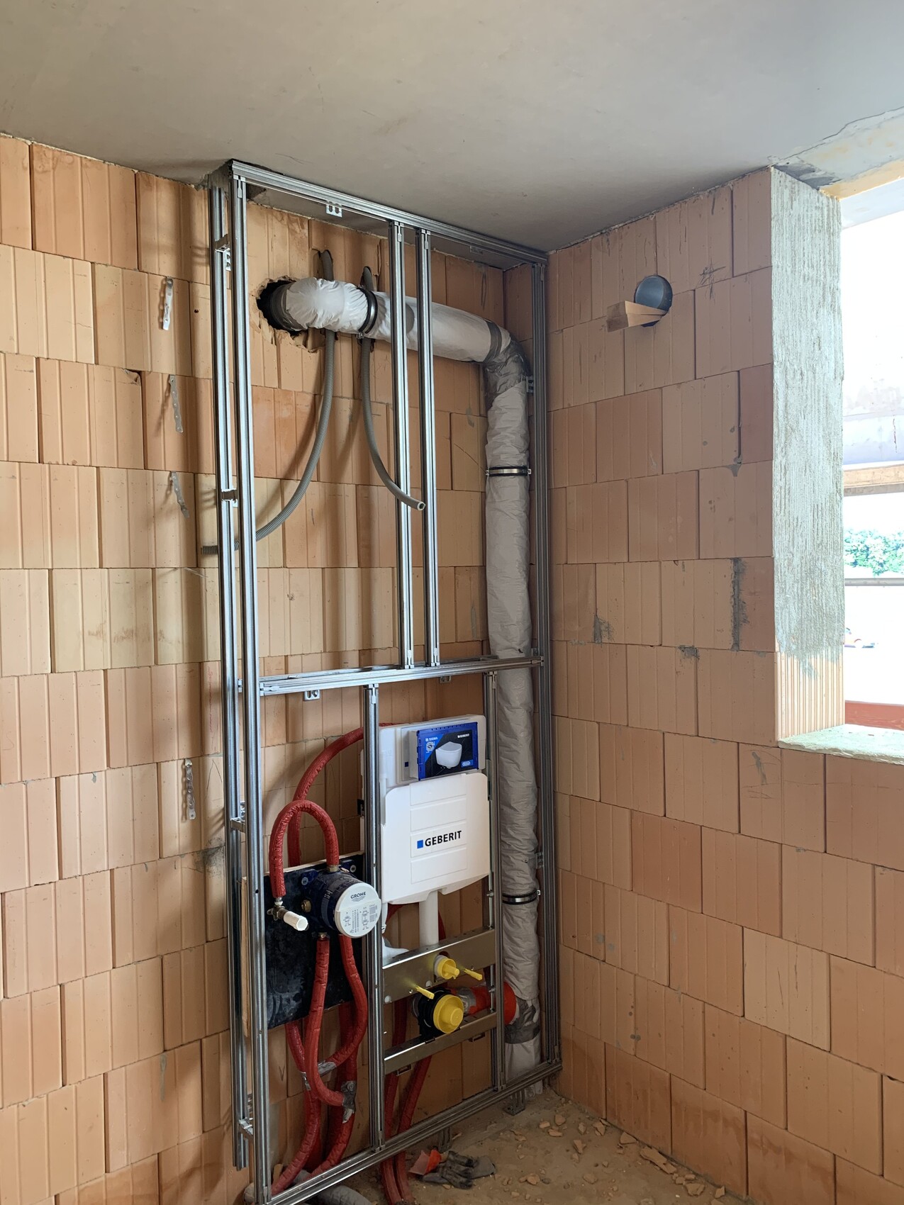 Rough construction of a bathroom: Geberit installation frame with pipes and insulation.