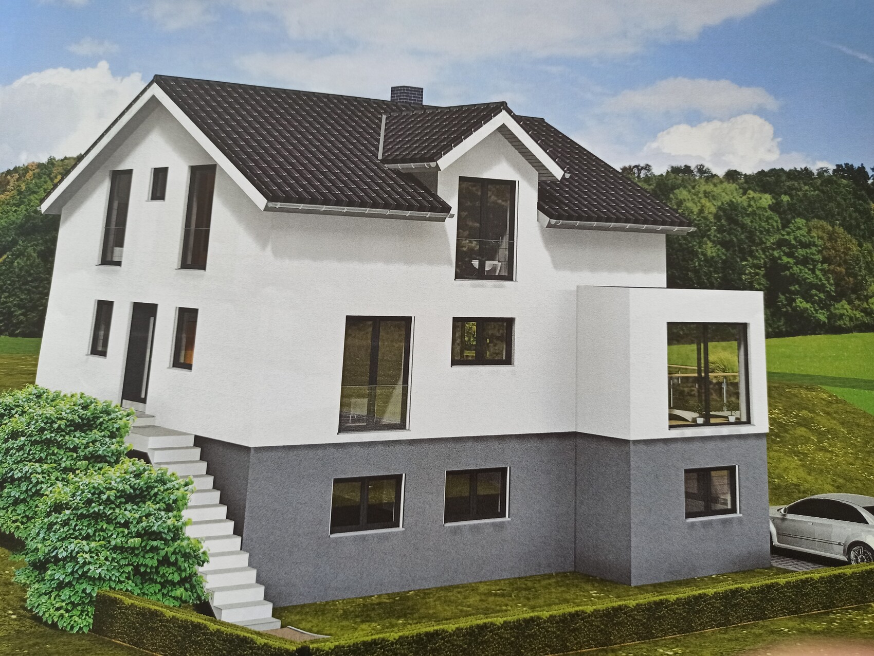 Modern white house with gray plinth and large windows in a green environment.