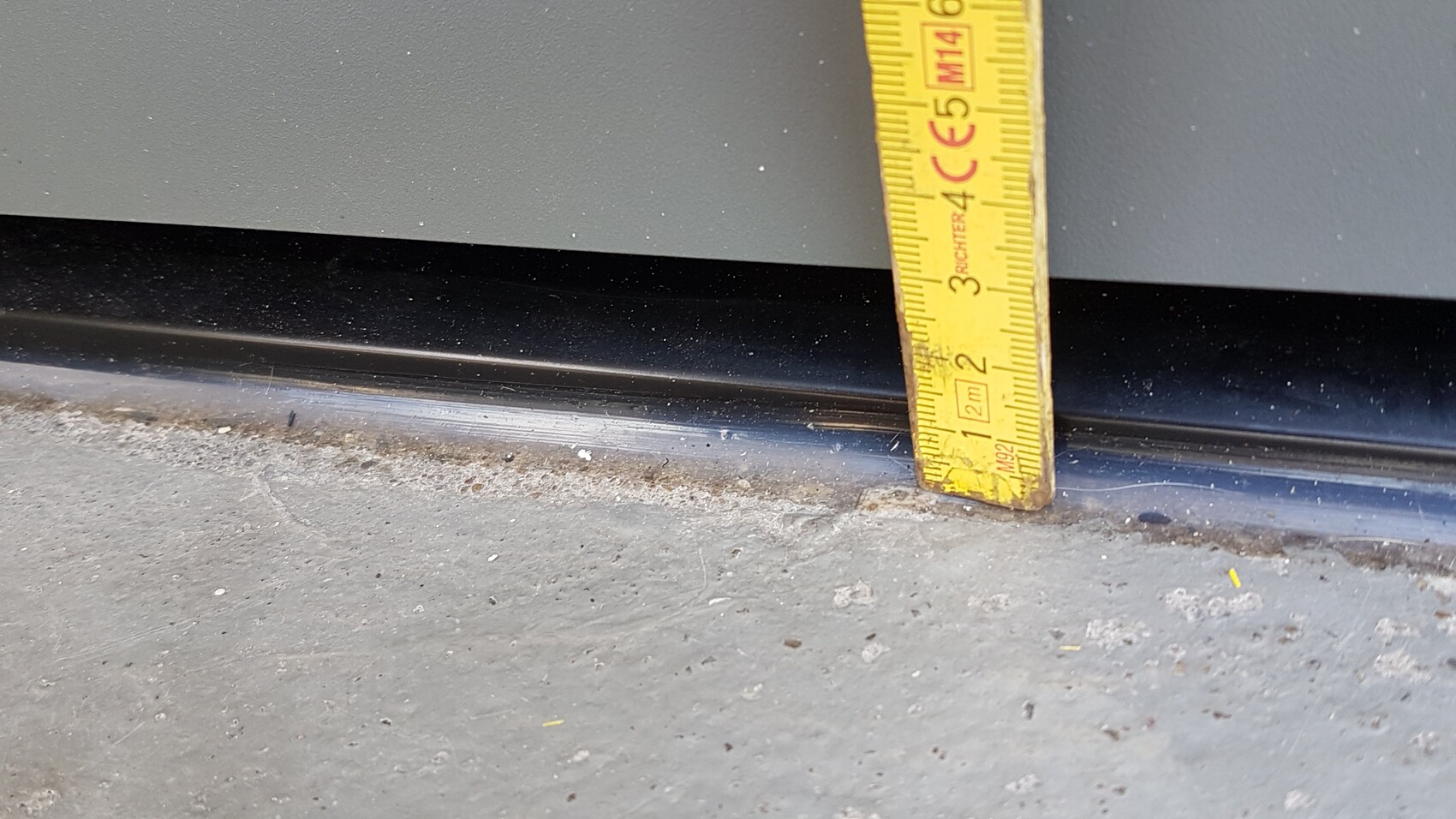 Nahaufnahme eines gelben Maßbands neben einer Türschwelle am Boden.