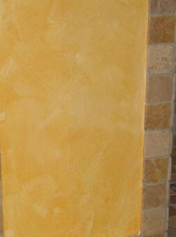 Exterior wall with yellow plaster next to stone wall