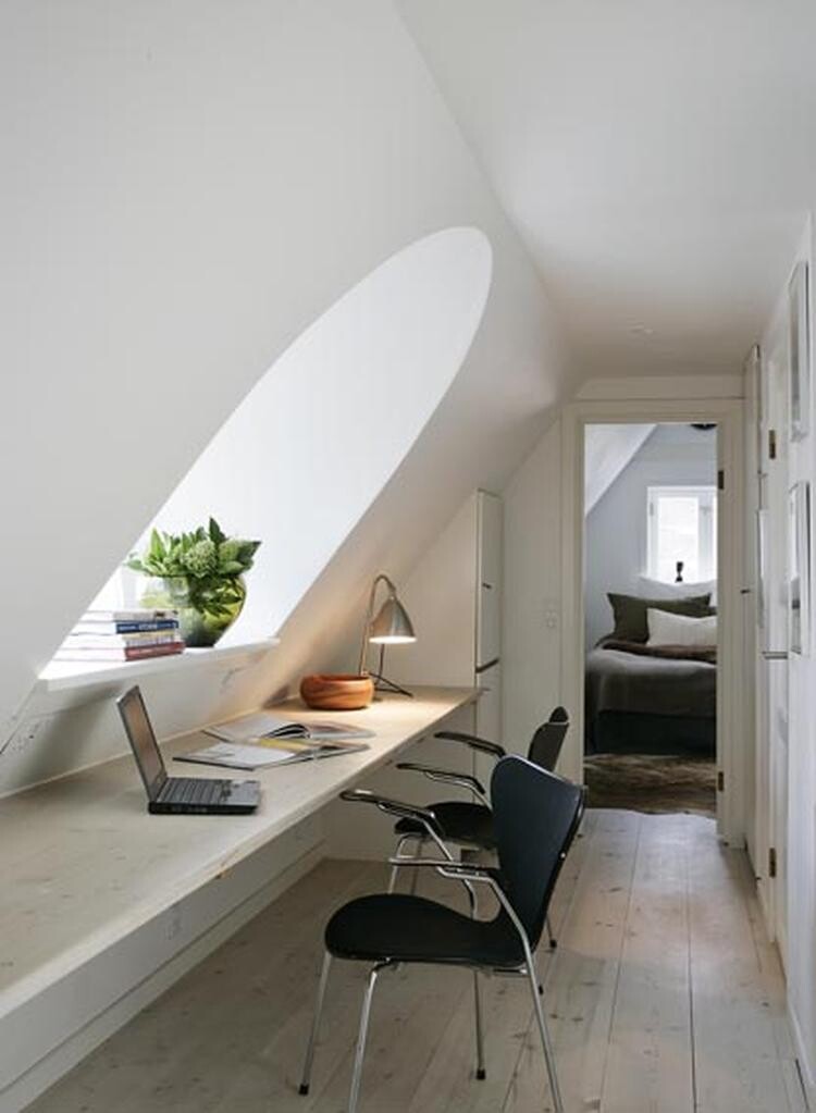 Working area in the attic: laptop, plant, books; three chairs, view into the bedroom.