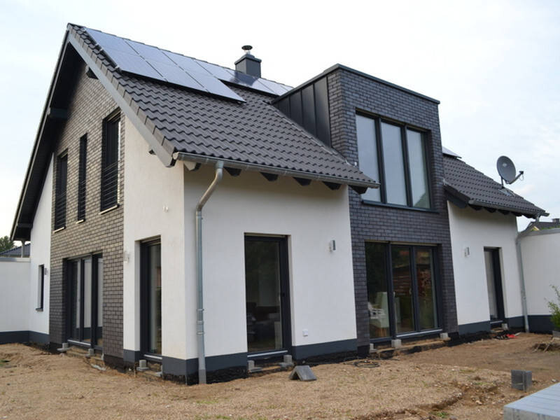 Modern single-family house with white facades, dark accents, and solar panels on the roof