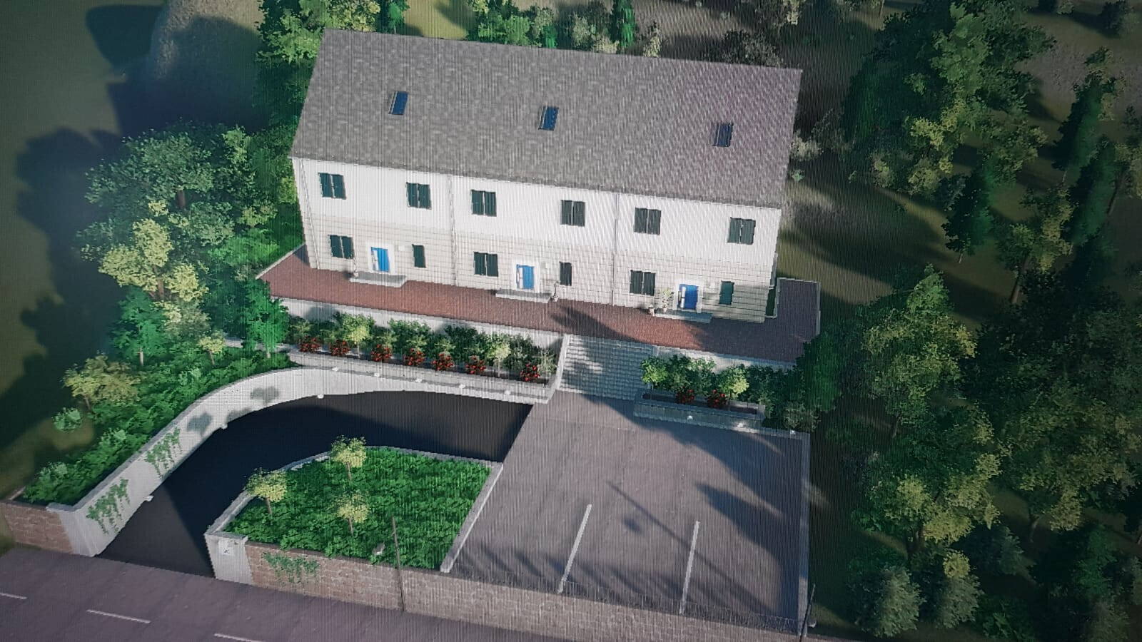 Aerial view of a row housing complex with white facades, blue doors, garden areas, and a parking lot.