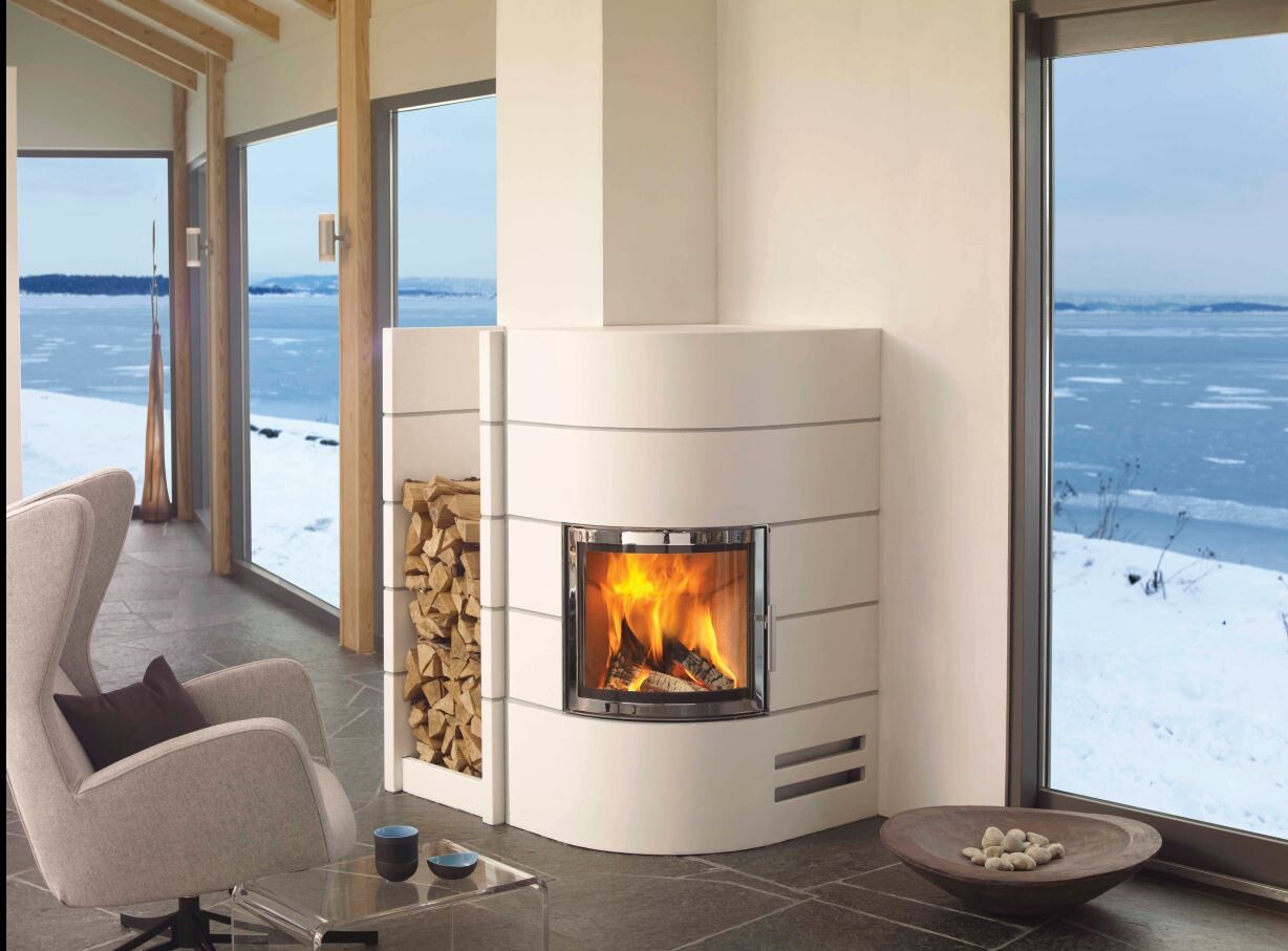 Moderne weiße Kaminanlage mit Holzvorrat; gemütliche Sitze, Fenster mit verschneiter Landschaft.
