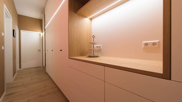 Bright hallway with white cabinets, wooden countertop, and illuminated wall niche.