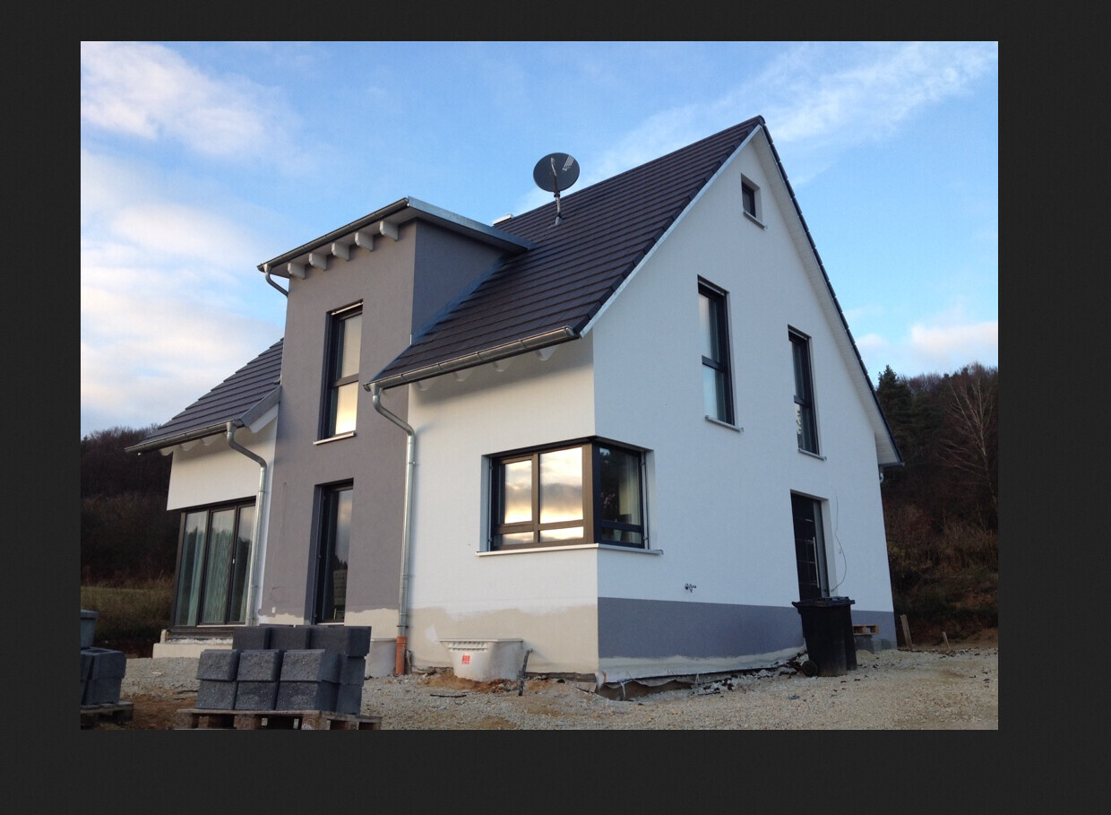 New house under construction: white and gray facade, roof, windows, construction materials