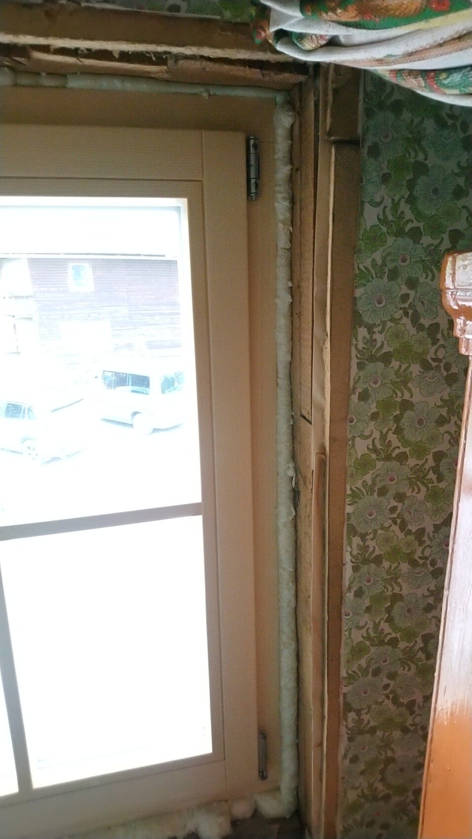 Window frame in renovation area; exposed wall, insulation pipe, green wallpaper.