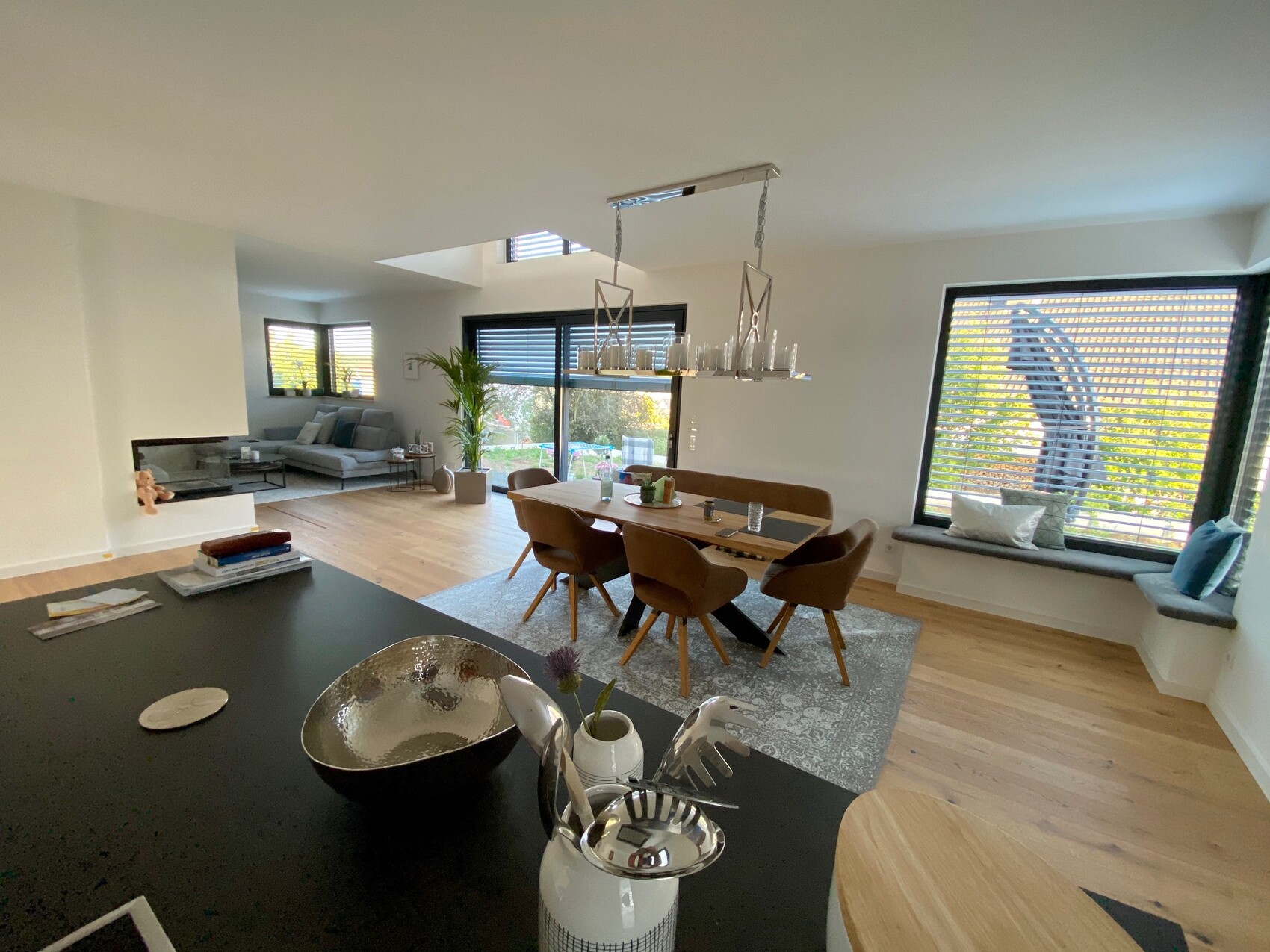 Open living and dining area with dining table, sofa, window front, and plant.