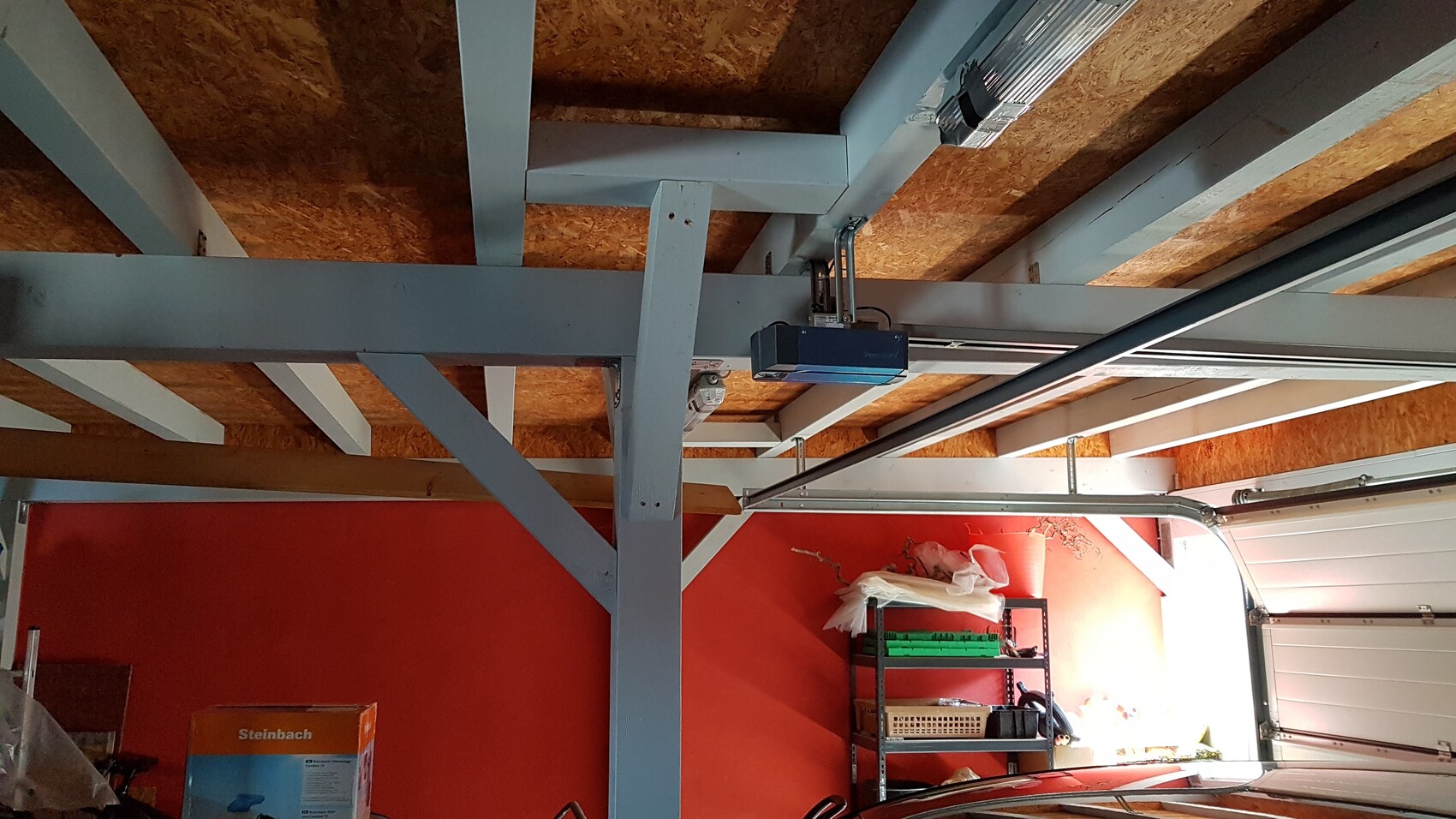 Garage with visible steel beams, ceiling joists and shelves inside