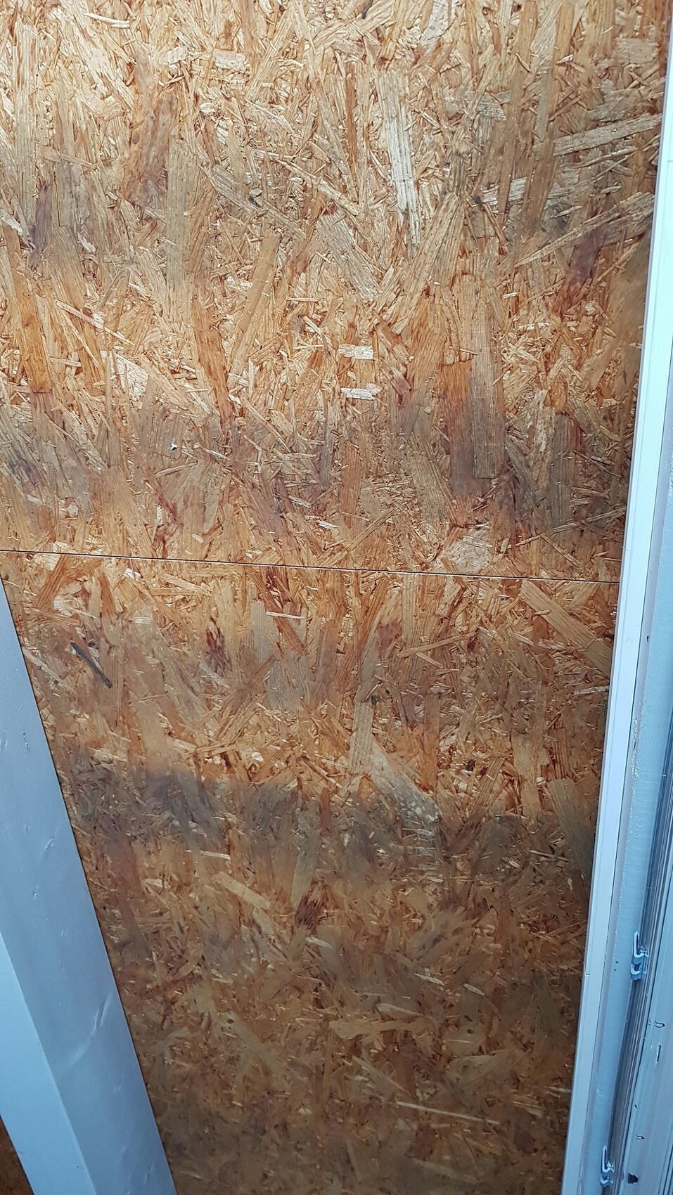 Room with OSB wall covering, door frame at the edge, construction site scene.