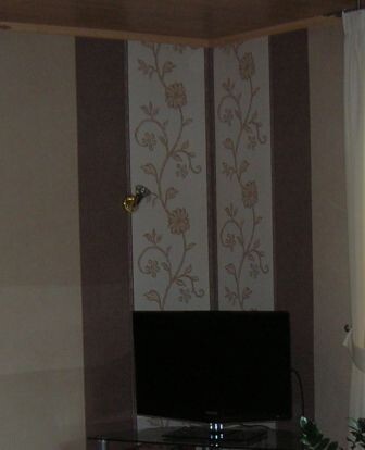 Living room with television, vertical stripes and floral wallpaper on the wall