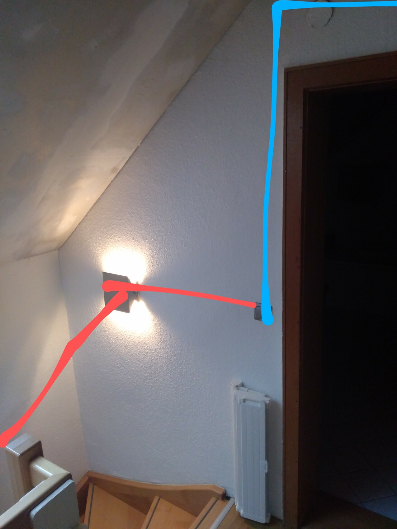 Stairwell with illuminated wall lamp; red line marks path from stairs to door, blue marking on door frame.