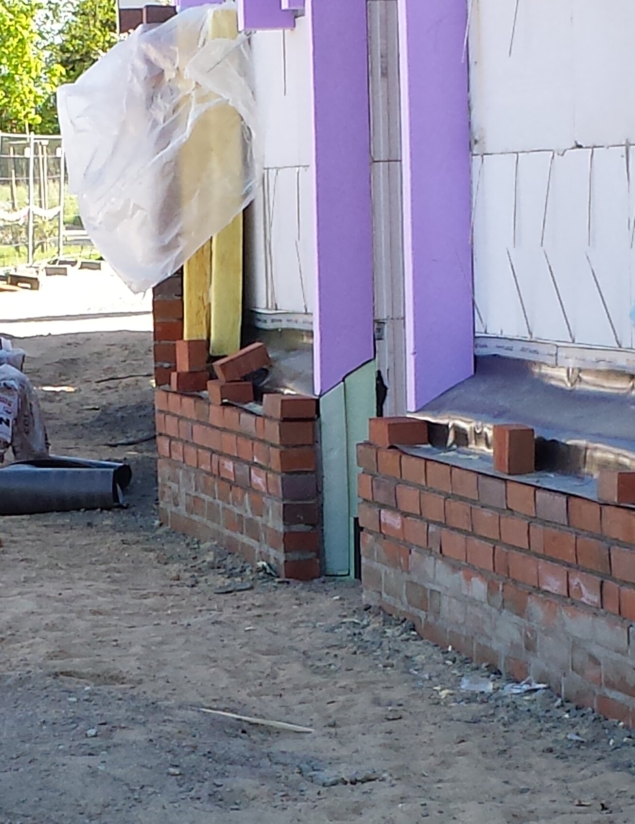 Shell construction: Brick wall at foundation with purple insulation boards on the exterior wall