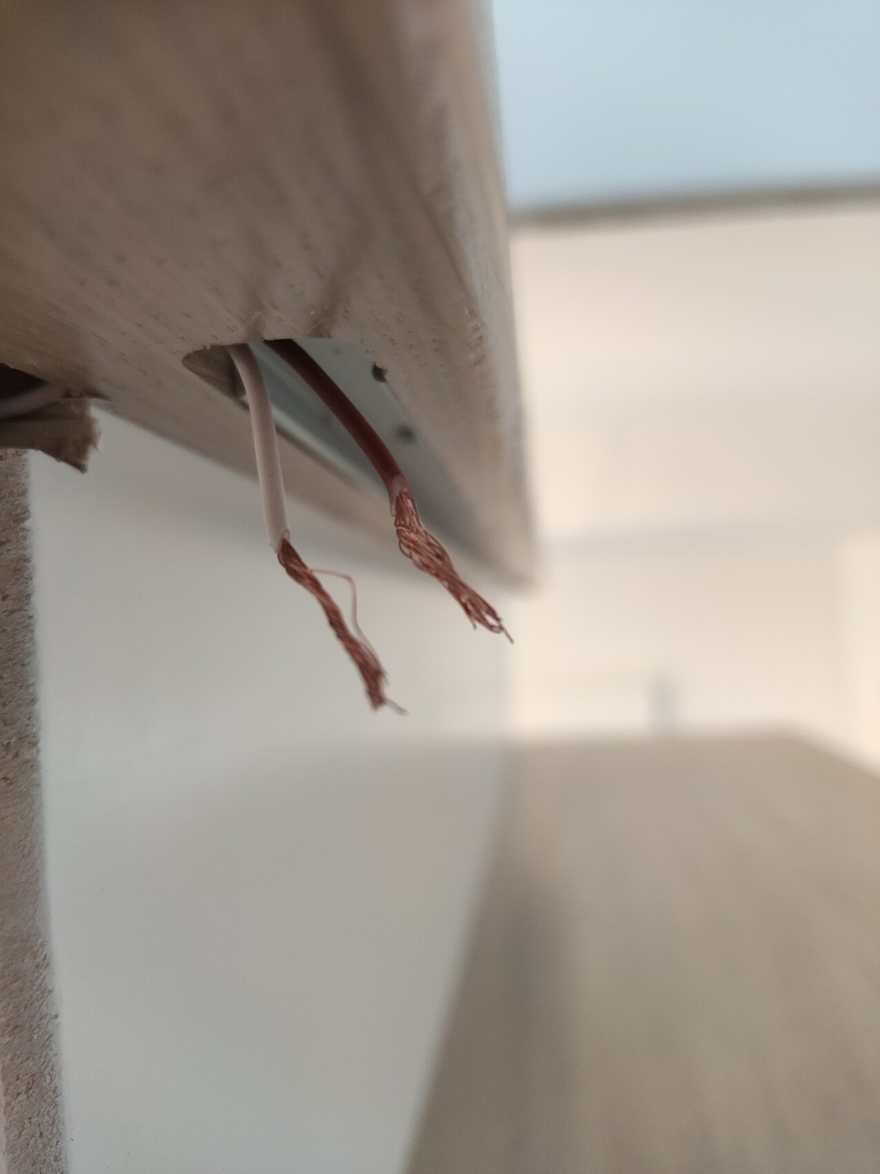Copper strands of cables exposed under a wooden cladding.