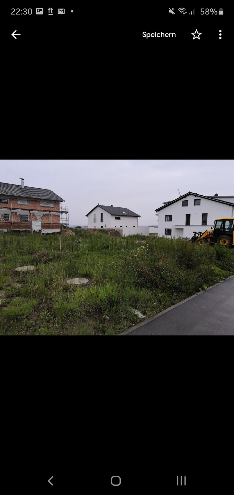 Baugebiet mit drei Häusern: links Gerüst am Backsteinhaus, rechts Bagger, Unkrautfläche.