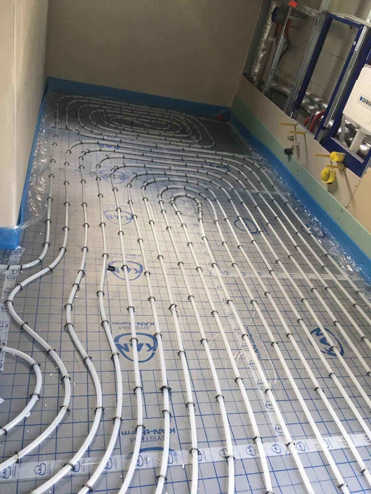 Underfloor heating pipes arranged in a spiral pattern on insulation in the utility room.