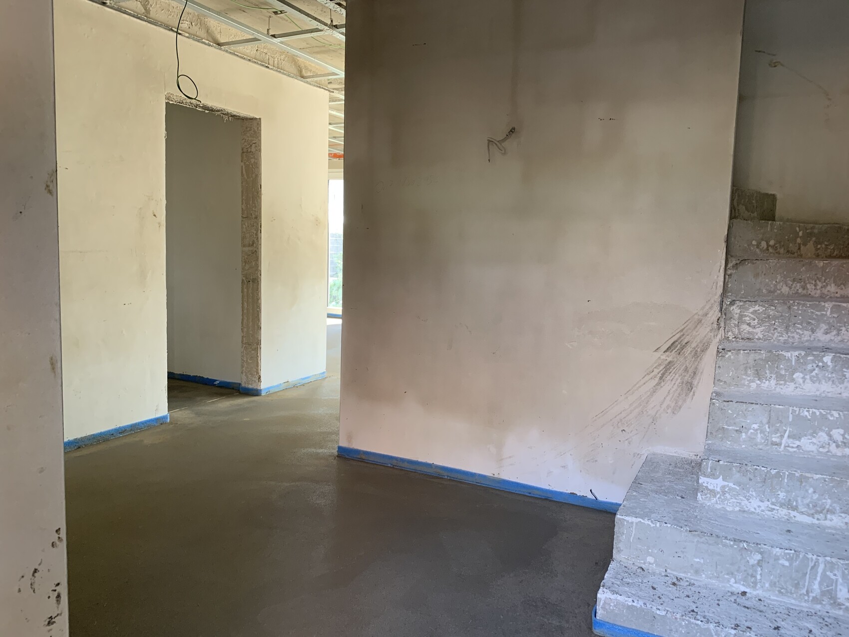 Unfinished interior: wall surfaces, stairs on the right, open doorway on the left, cable connection.