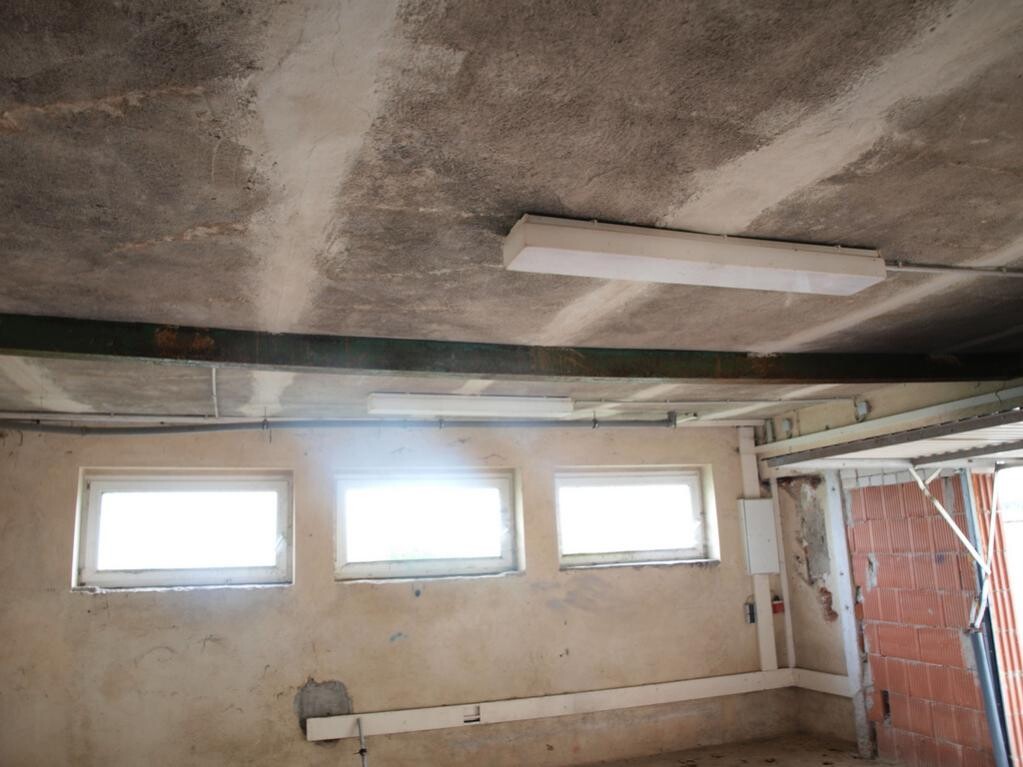Unfinished basement room with raw concrete ceiling, small windows and installations
