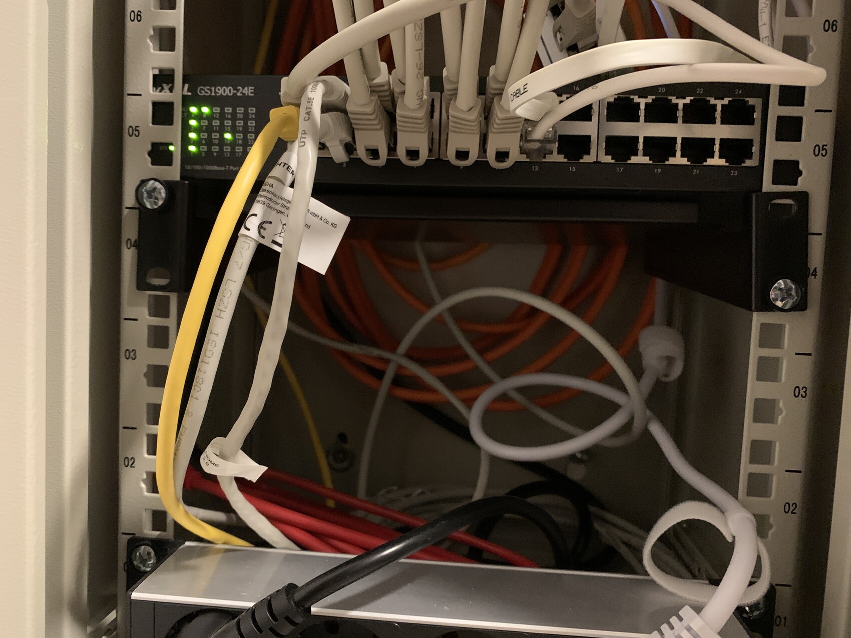 Network cabinet with switch, green LEDs, patch cables in yellow/white/orange/red