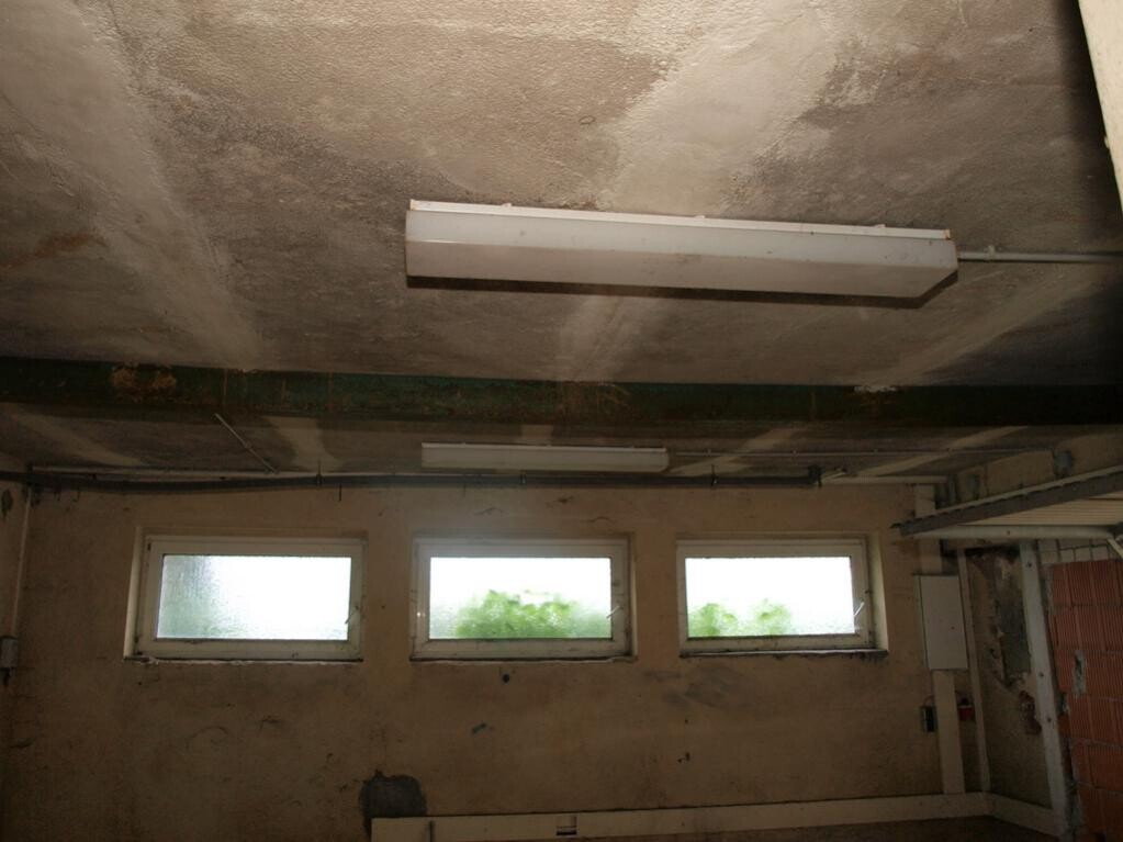 Basement room in shell construction with rough ceiling, windows and visible installations