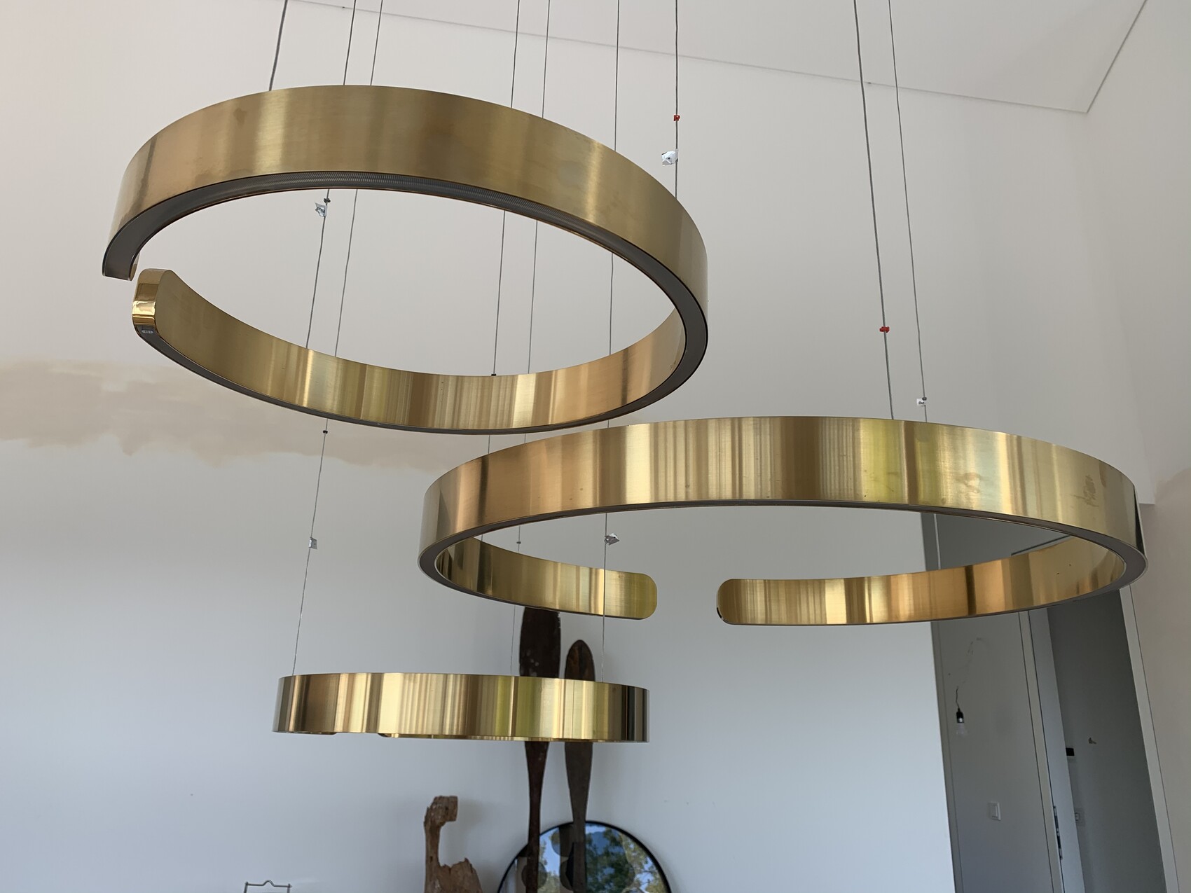 Several large golden metal rings hang as modern pendant lights on cables from the ceiling.