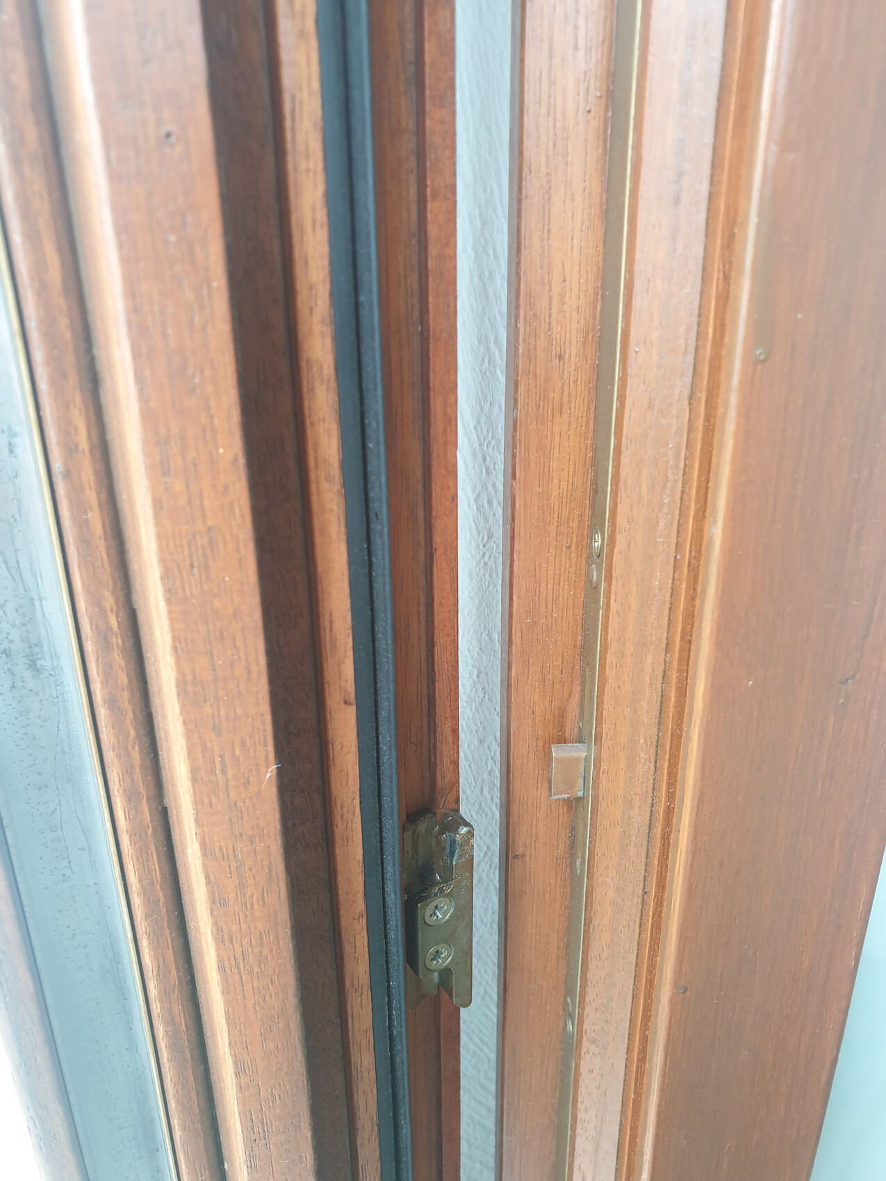 Close-up of a wooden door frame with small metal fitting and screws