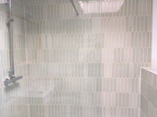Bright bathroom with shower, glass partition and tiled walls