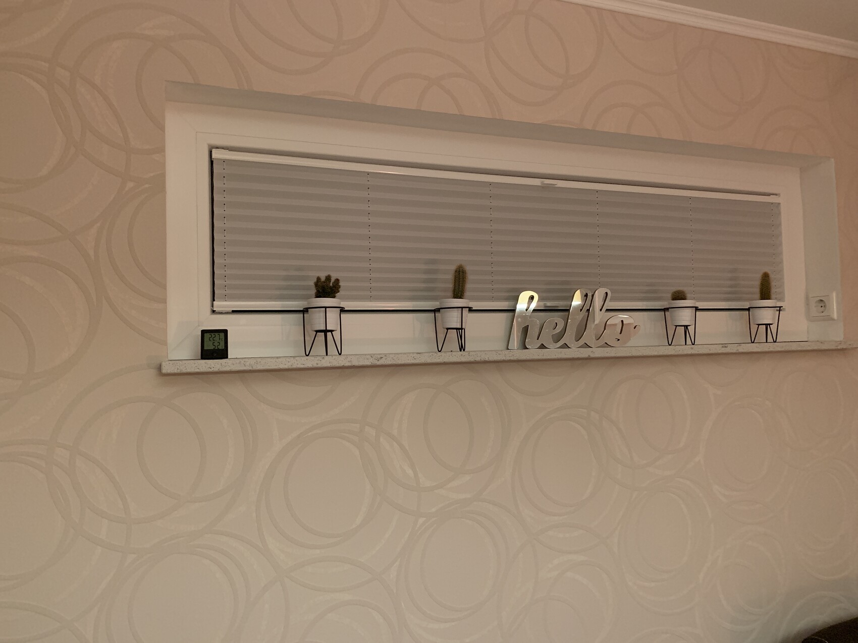Windowsill with blinds, small cacti in metal pots, and the lettering 'hello'.