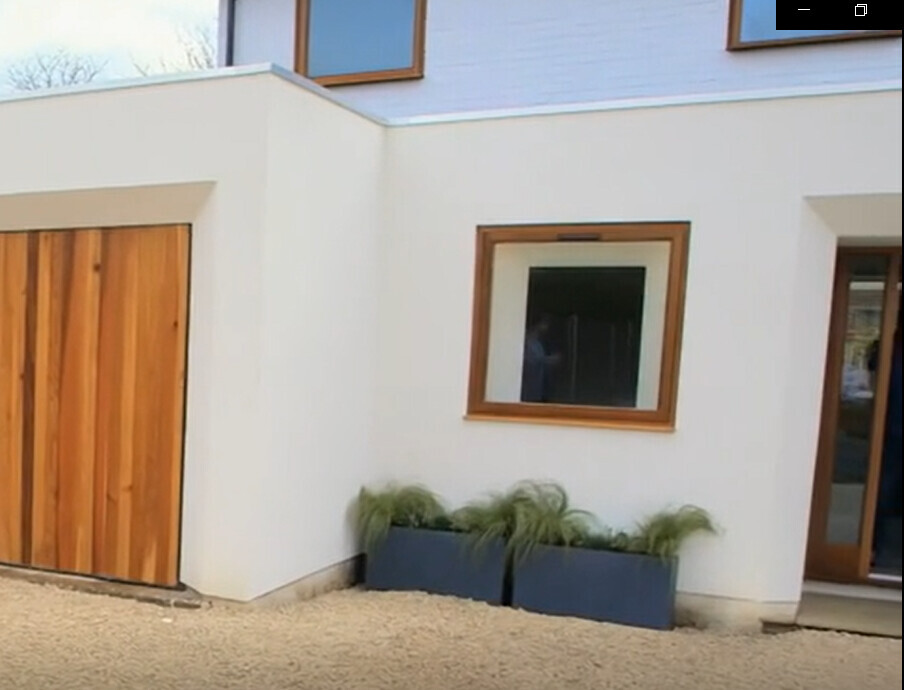 Modern house facade: white wall, wooden windows, wooden doors, glass door, planter with grass