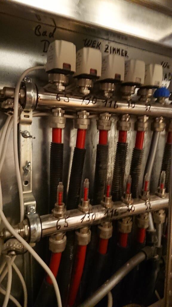 Heating and hydraulic piping: metal pipes, red hoses, valves with white handles.