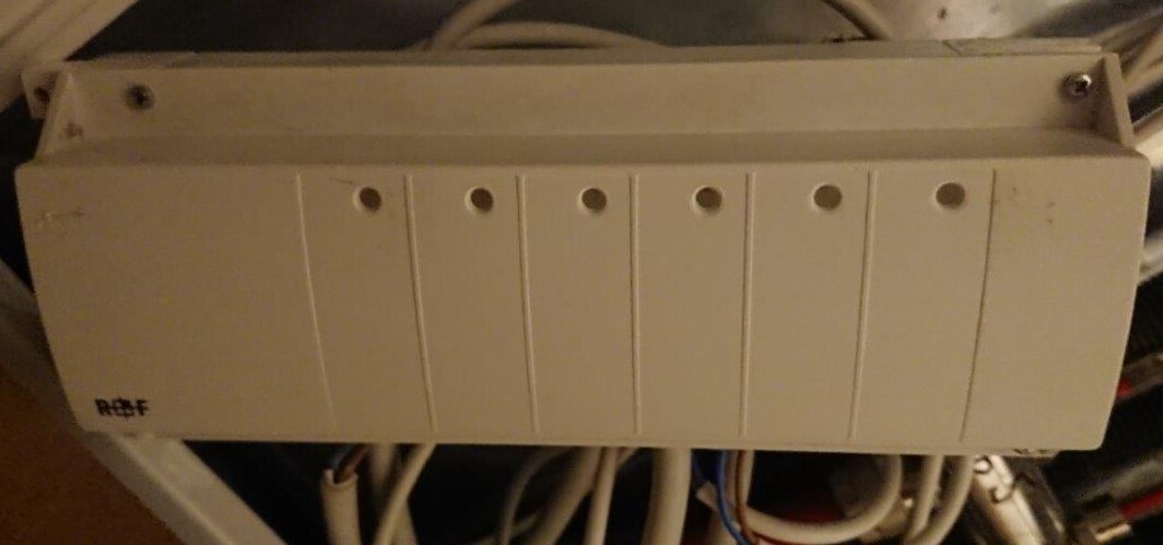 White distribution cabinet with seven vertical compartments, with cable bundles underneath.