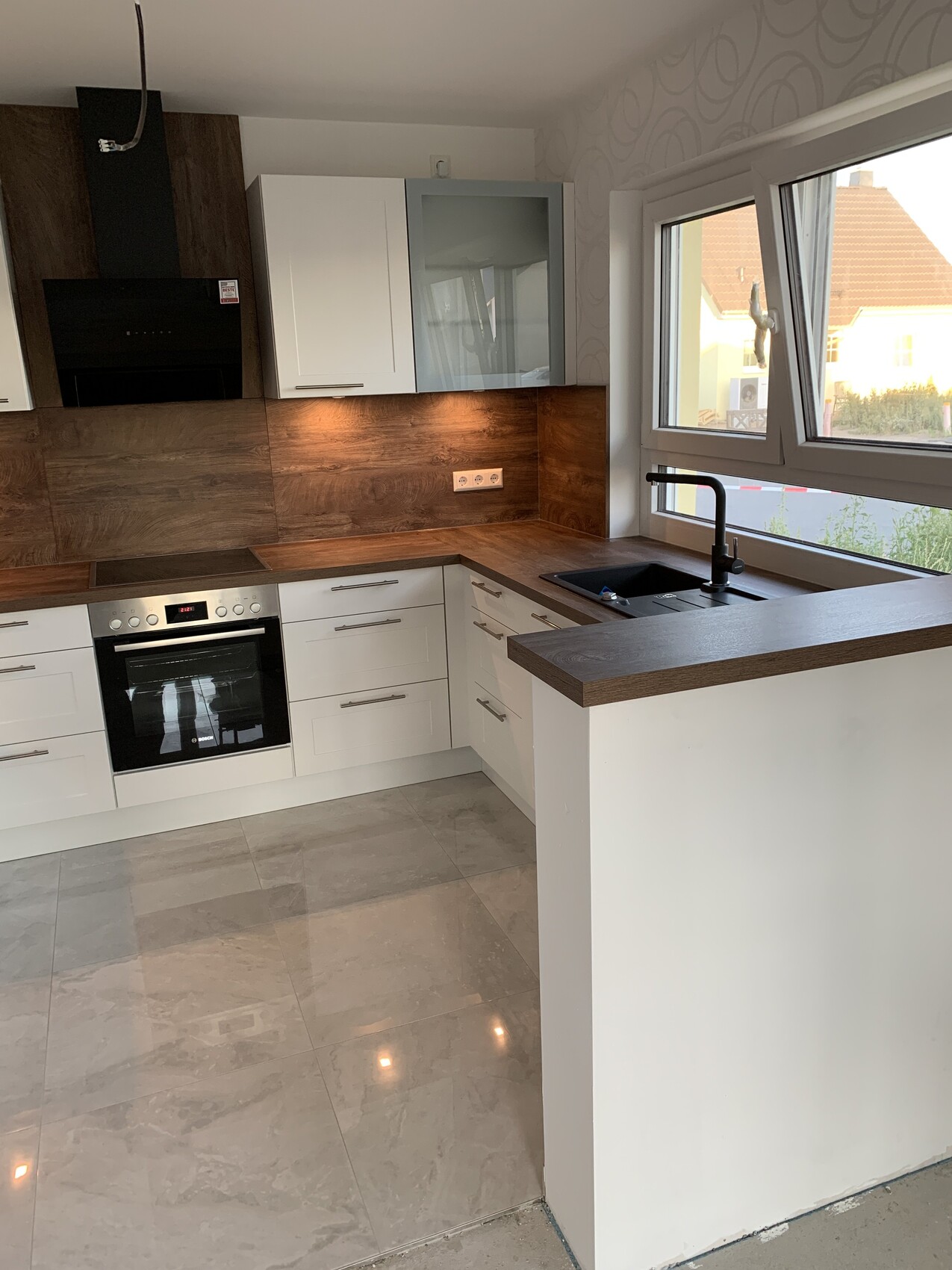 Modern kitchen with white cabinets, wood countertops, oven, sink by the window.
